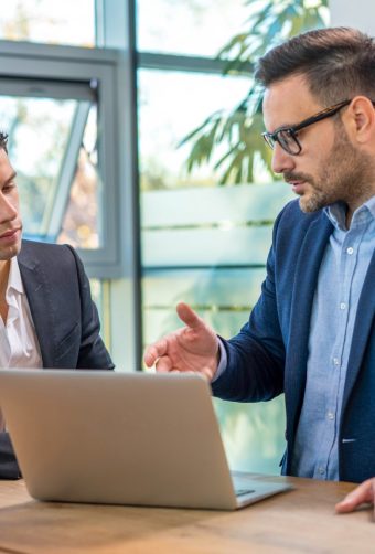 Businessman explaining something to a colleague using a laptop at office. Conseiller clientèle particulier