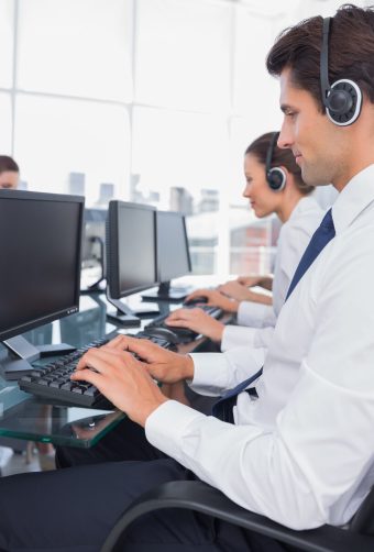Group of call center employees working on computers in a bright office Group of call center employees working on computers in a bright office